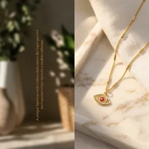 Detail of evil eye pendant with red drip oil finish and gold bamboo cuban chain
