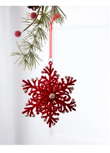 Detail of red flocked snowflake ornament with silver glitter on a Christmas tree branch