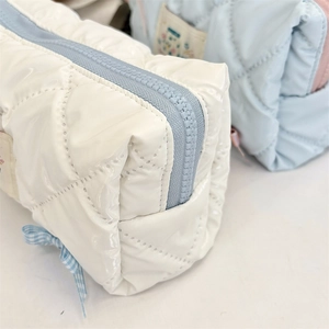 Detail of white glossy pencil case with blue bow and diamond stitching pattern