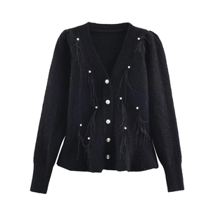 Detailed view of the elegant pearl buttons and black feather trim on a knit cardigan