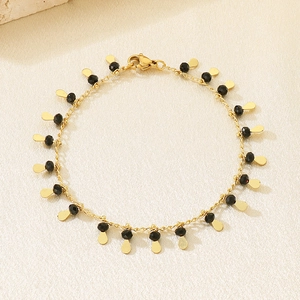 Detailed shot of golden link bracelet featuring black beads and small teardrop charms