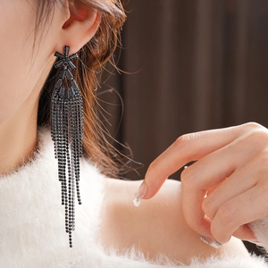 Gros plan sur un mannequin portant des boucles d'oreilles à pompons noirs et zircons