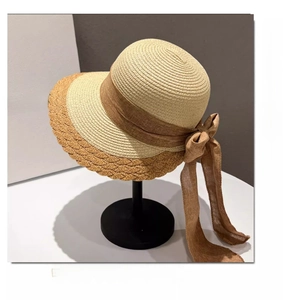 Detail of wide brim straw sun hat with wavy contrast edge and long ribbon bow