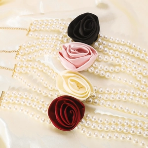 Detailed view of triple-strand pearl necklaces with fabric roses in four colors