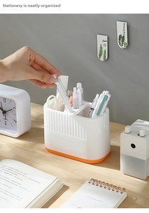 Close-up of a white and orange desk organizer with four sections for pens and stationery