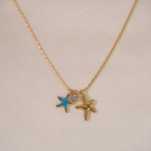 Macro detail of gold sea star pendants and sparkling rhinestones on a silk background