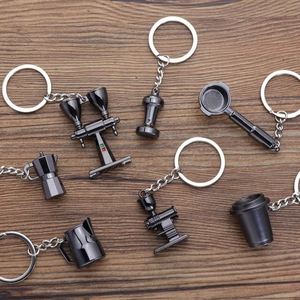 Gunnmetal alloy coffee theme keychain set featuring moka pot and tamper on wood background
