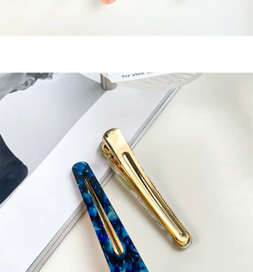 Close-up of marble acetate and gold metal drop-shaped hair clips for women