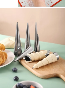 Macro shot of stainless steel conical baking molds and dough wrapped on croissant tubes