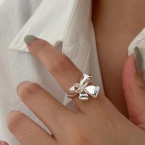 Detail shot of a polished S925 silver bow-knot ring worn on finger with elegant style