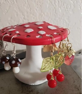 Detail of mushroom jewelry stand holding cherry and strawberry resin earrings for display