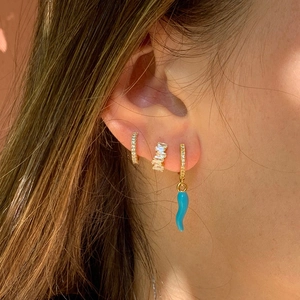 Detailed close-up of stacked gold earrings with blue cornicello charm and zircon inlays