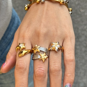 Two-tone stainless steel jewelry set with star and flower motifs on a model's hand