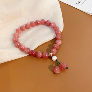 Close-up of pink strawberry quartz bracelet with a white pearl and crystal charms