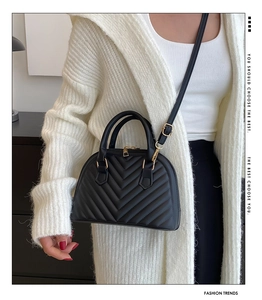 Detail of black quilted shell bag with gold hardware and removable shoulder strap