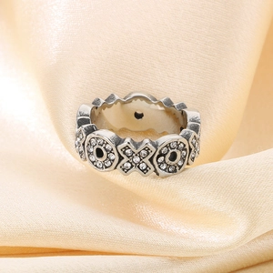 Macro shot of vintage silver ring with XO pattern and pavé micro zircons on silk background
