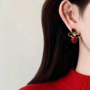 Close-up of vintage resin flower earring with deep red petals and crystal detail on ear