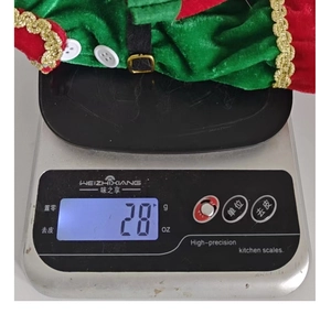 Detail of Christmas elf bottle cover made of red and green velvet weighing 28g on scale