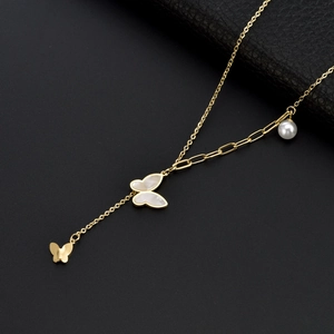 Gold butterfly necklace with shell pendant and pearl decoration on a dark textured surface