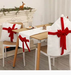 Detail of white plush Christmas chair cover and table runner with festive red bows
