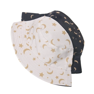 Detail of navy and white bucket hats with golden moon and star patterns on cotton fabric