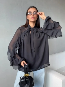 Detail of elegant black chiffon shirt featuring a tied bow neck and tiered ruffle sleeves