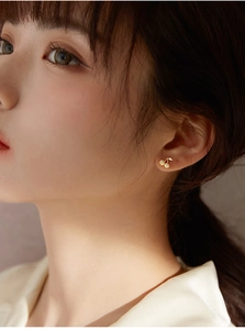 Macro shot of gold cherry stud earrings featuring sparkling crystals on a female model