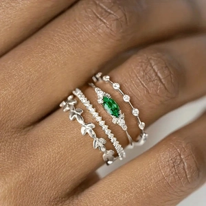 Juego de cuatro anillos plateados con piedra verde, motivos de hojas y detalles brillantes