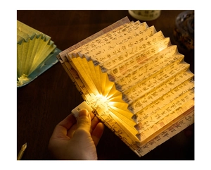 Macro shot of an open fan-shaped book lamp with Chinese calligraphy and warm LED light