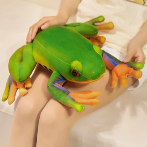 Large green tree frog plush toy with orange feet shown in a high-quality lifestyle setting