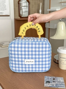 Detail der blau karierten Kosmetiktasche mit gelbem Griff und Doppelreißverschluss