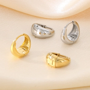 Polished gold and silver U-shaped hoop earrings on elegant champagne satin fabric