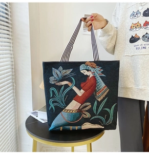 Detail of navy canvas tote bag featuring ethnic embroidery and striped woven handles