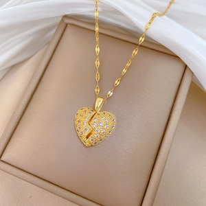 Macro detail of gold-plated titanium double heart pendant with sparkling crystals