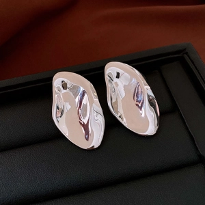 Macro shot of irregular fluid silver earrings with polished mirror finish on leather box