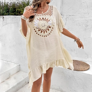 Detail of bohemian crochet beach cover-up with intricate patterns and fringe hem