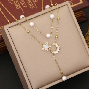 Detail of gold double-layered pearl necklace with star and moon charms on jewelry box
