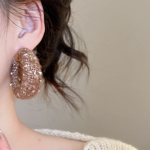 Nahaufnahme von Model mit braun gestrickten runden Creolen im minimalistischen Design