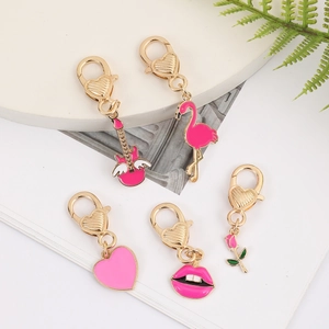 Pink enamel heart lobster clasp charms with flamingo and rose motifs on a white podium