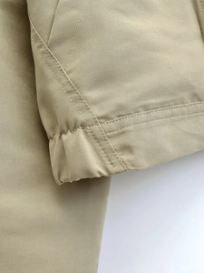 Close-up of beige drawstring jacket showing high-density fabric and double stitching detail