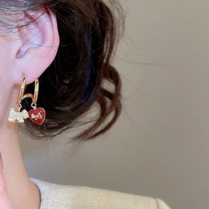 Detail of gold-plated hoop earrings with red heart and sparkling puppy pendant