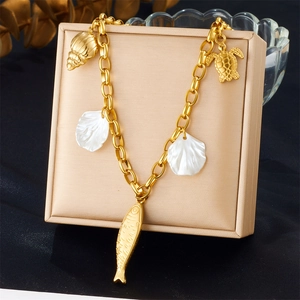 Detail of gold chain bracelet featuring sea turtle, fish, shell, and conch charms