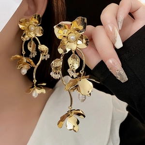 Close-up of gold flower earrings with pearls and crystals worn by a model