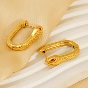 Boucles d'oreilles serpent en acier doré avec yeux rouges sur présentoir en marbre
