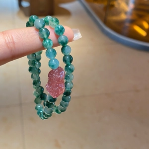 Detail of beaded bracelet with green agate beads and pink strawberry quartz Pixiu charm