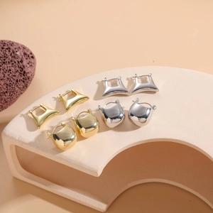 Detailed display of geometric saddle and dome earrings in gold and silver finishes
