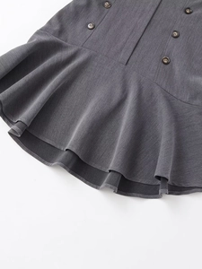 Détail d'une robe grise courte avec ourlet à volants superposés et boutons à double boutonnage
