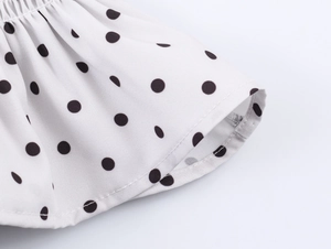 Close-up of white fabric with black polka dots showing hem stitching and soft texture