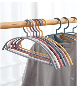 Detail of multi-colored non-slip plastic hangers holding a grey T-shirt on a wooden rod