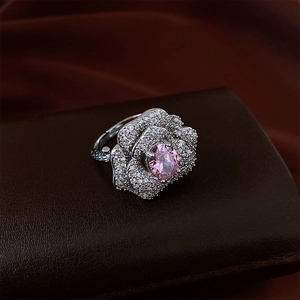 Macro shot of rose-shaped silver ring with pink gemstone and pavé micro-diamonds
